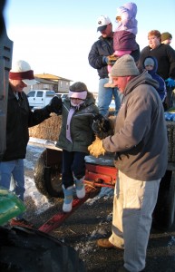 The men help carolers step on the wagon tongue then to the ground.