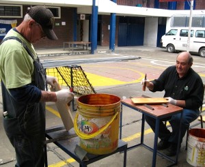 Men are varnishing the seats and backs for chairs.